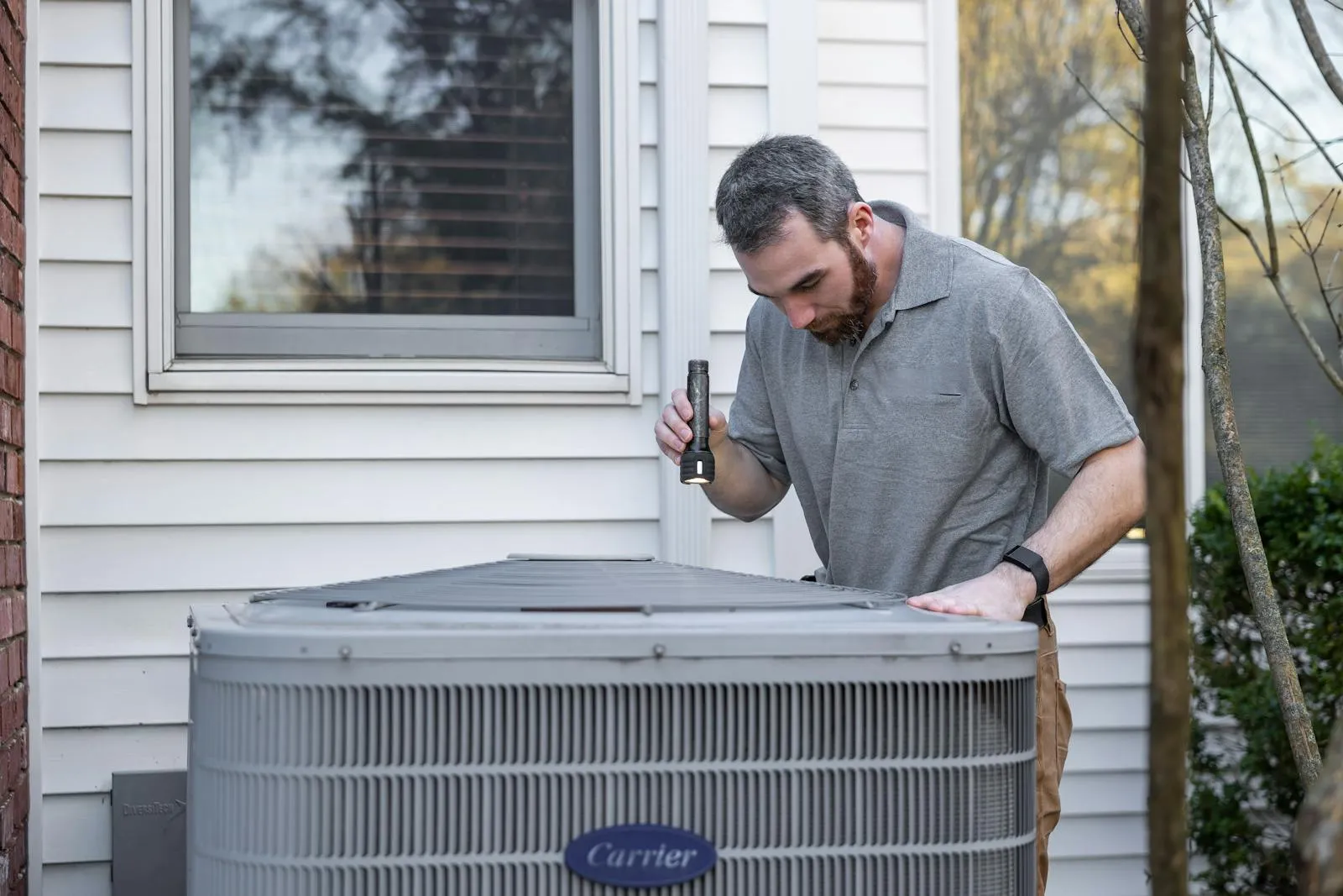 HVAC technician inspecting a residential condenser