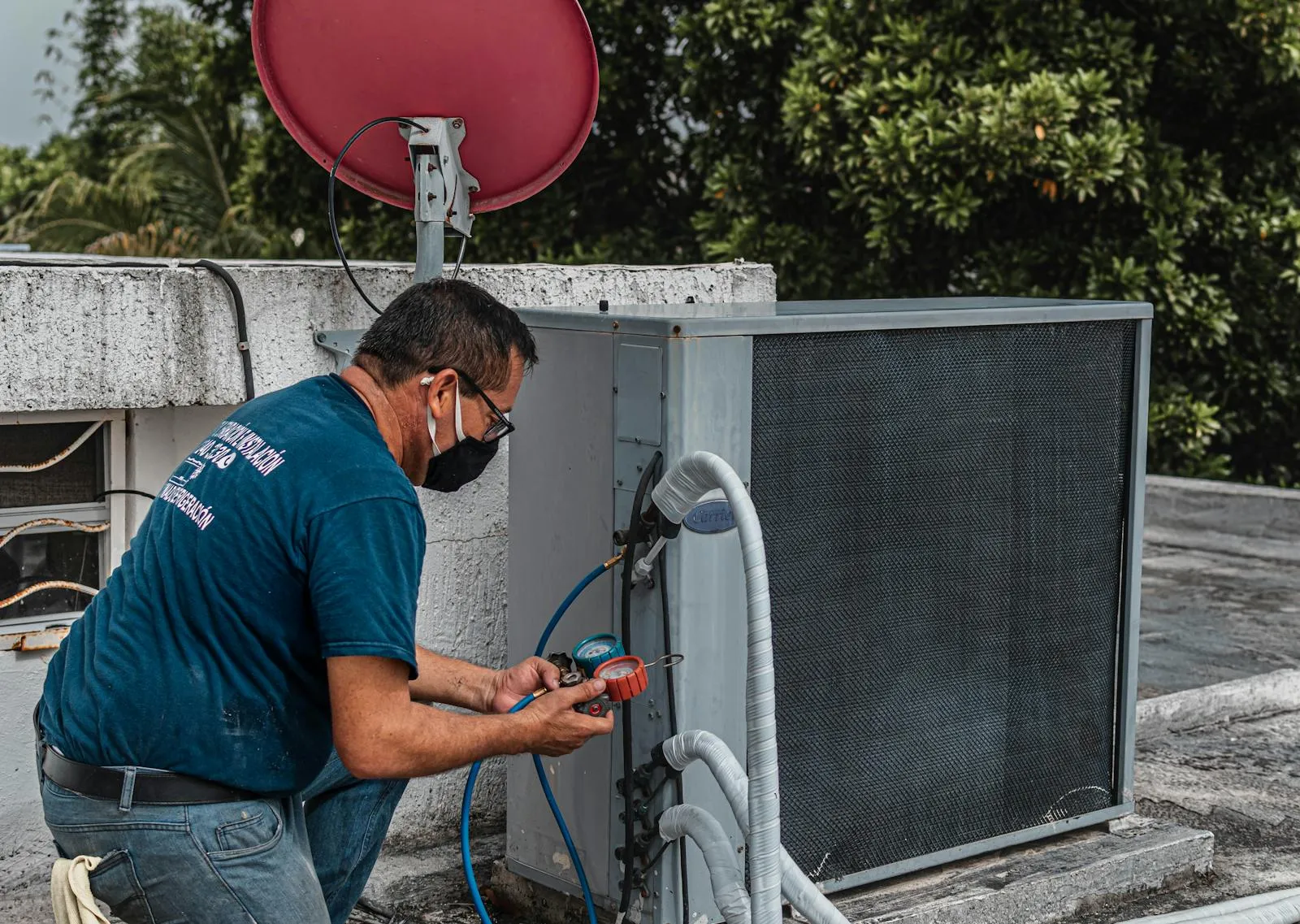 HVAC technician checking an outdoor air conditioning unit with refrigerant gauges